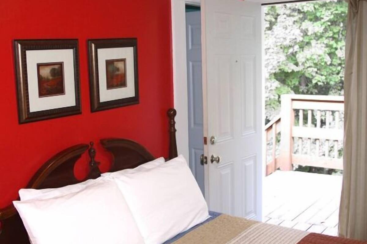 A bedroom with a bed, two framed pictures on the wall, and a door leading to an outdoor area.