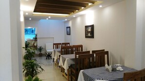 A dining area with wooden tables and chairs, potted plants, and framed artwork on the walls. - Lemon Tree Hotel (Kathmandu)
