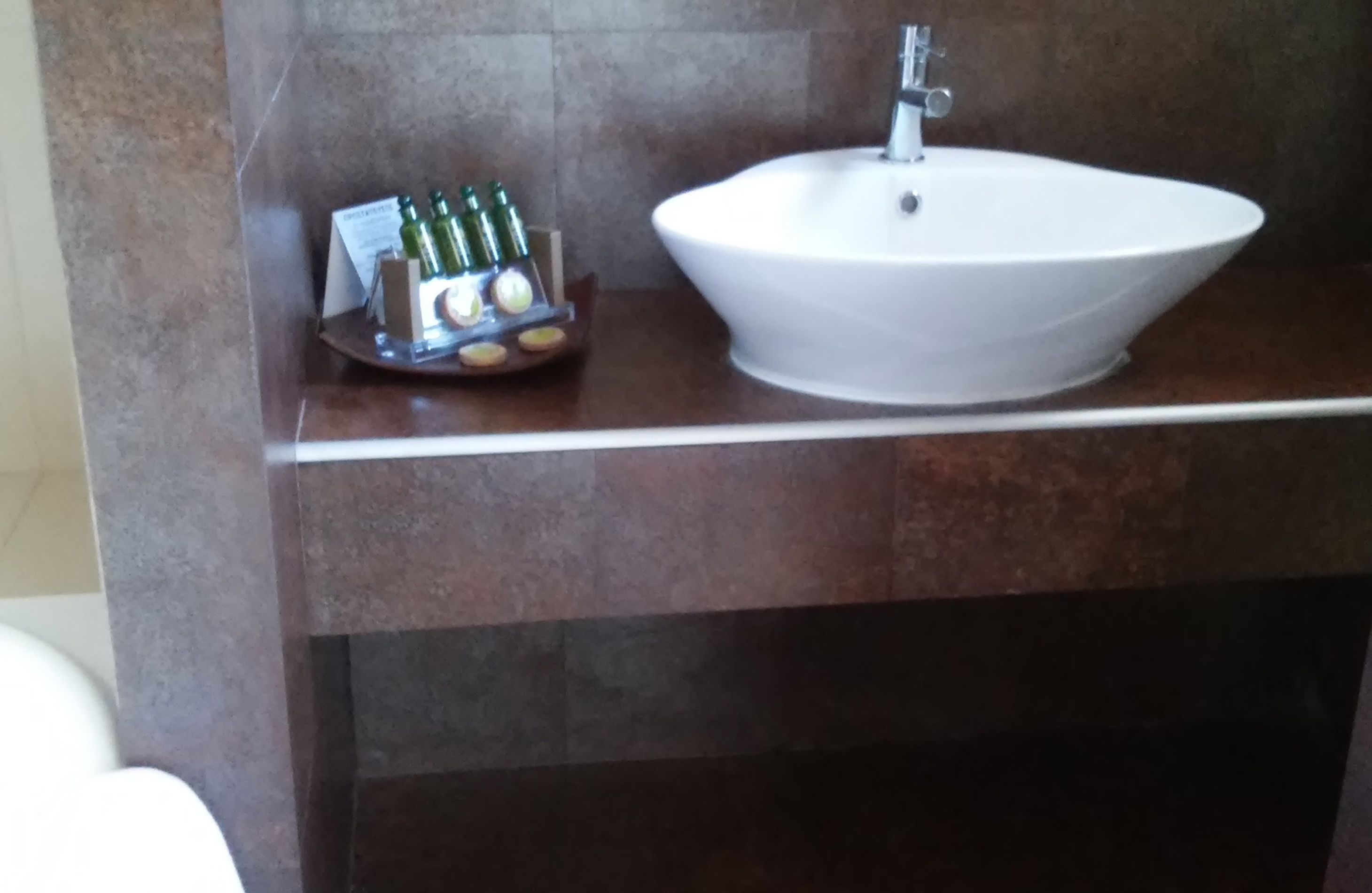 Un baño con un lavabo blanco y una bandeja con artículos de aseo.