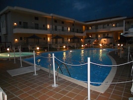 Una piscina al aire libre, sombrillas, sillones reclinables de piscina