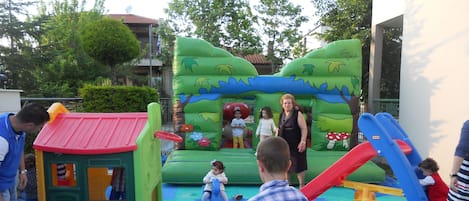 An outdoor play area with inflatable structures, a slide, and a playhouse.