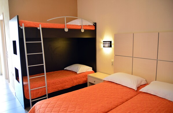 A room with bunk beds, a ladder, a bedside table, and a wall-mounted light fixture.