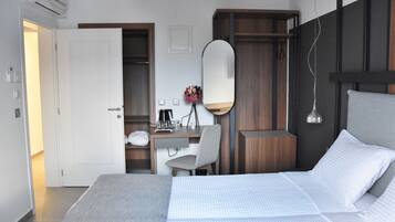 Ein modernes Hotelzimmer mit einem großen Bett, einem Schreibtisch mit Stuhl, einem Spiegel und einem Kleiderschrank.