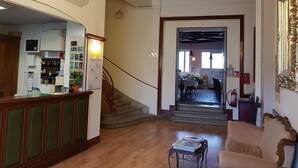 Zona de recepción con mostrador, escalera y comedor al fondo.