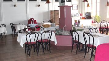 Un restaurant doté de nombreuses tables et chaises, de nappes blanches et de luminaires suspendus.
