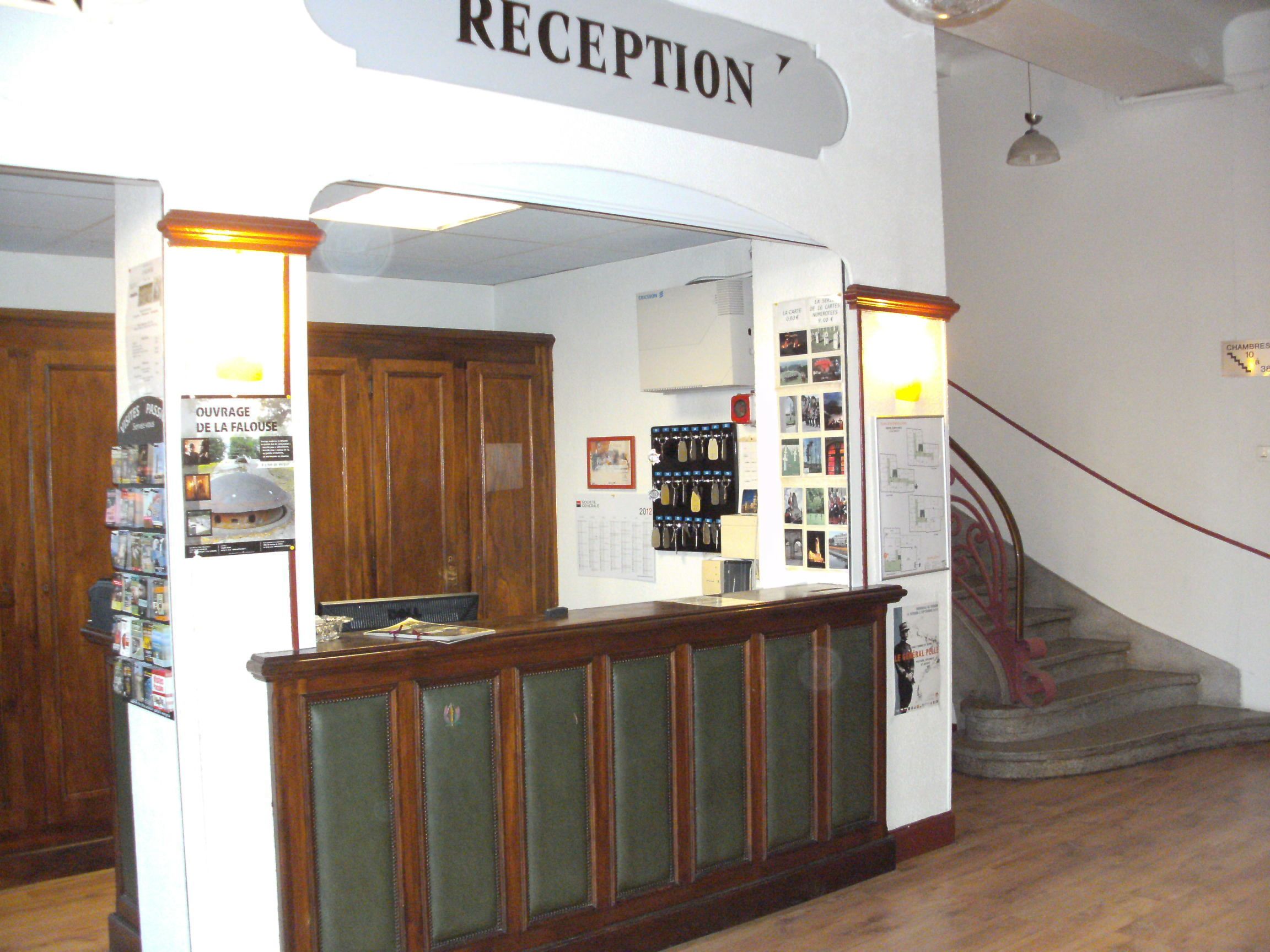 A reception area with a wooden counter, a sign above it reading "RECEPTION", and a staircase to the right.