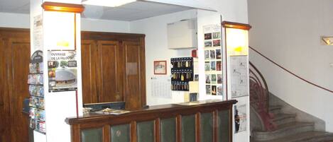 A reception area with a wooden counter, a sign above it reading "RECEPTION", and a staircase to the right.