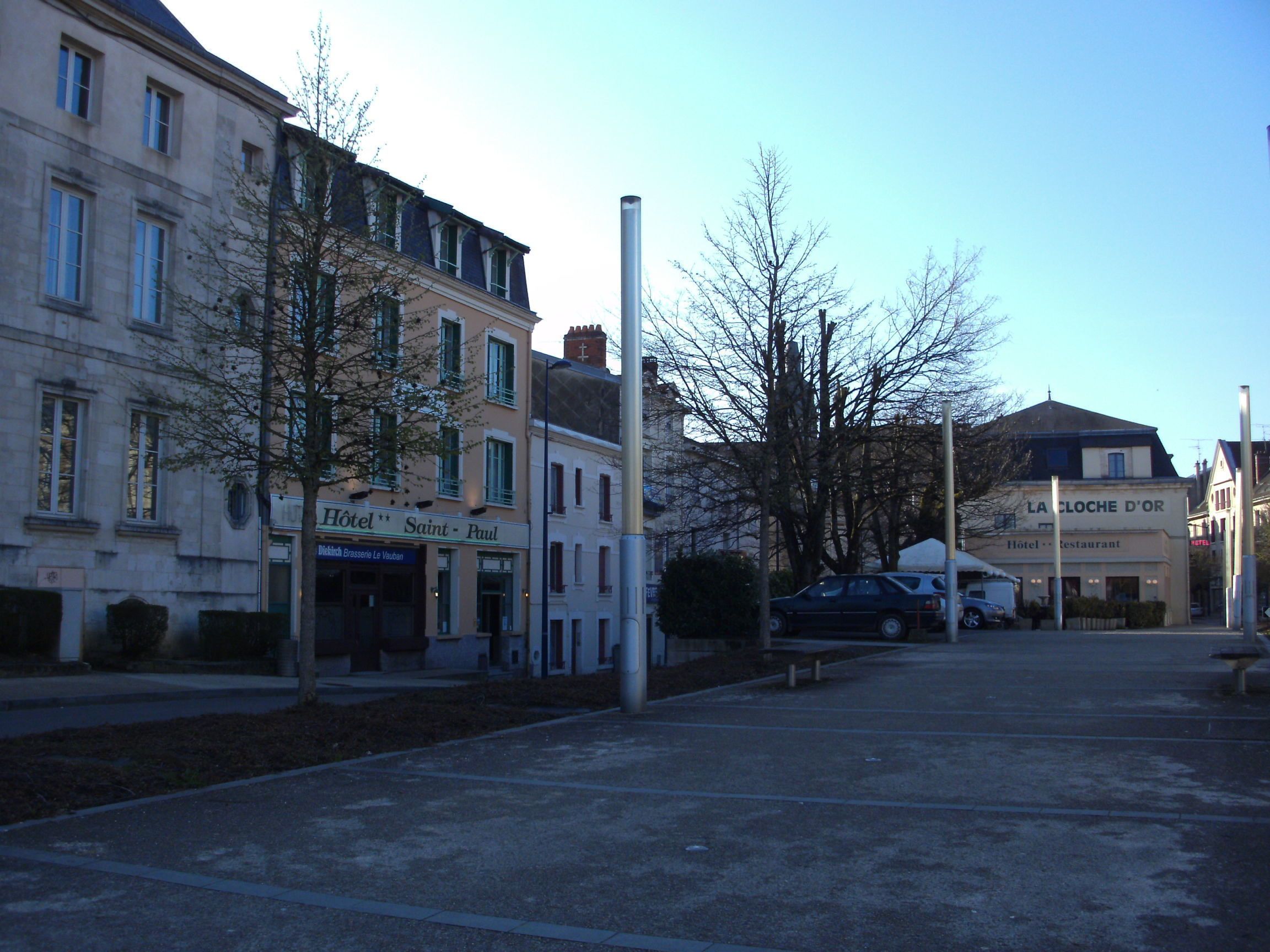 Een straat met gebouwen, waaronder het hotel "Hôtel Saint-Paul" en het restaurant "La Coche d'Or".
