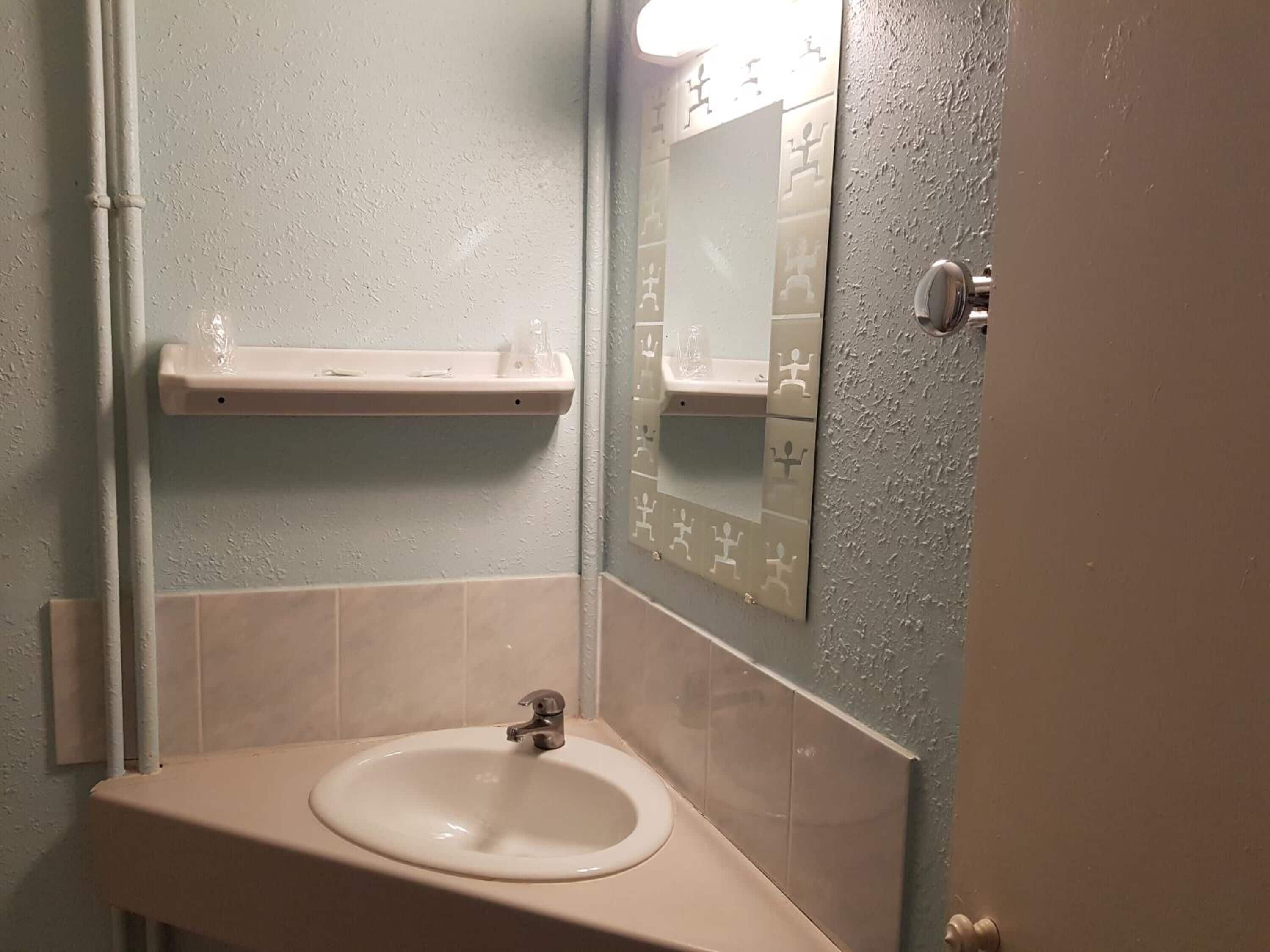 Ein Badezimmer mit Waschbecken, Spiegel und zwei Ablagen.