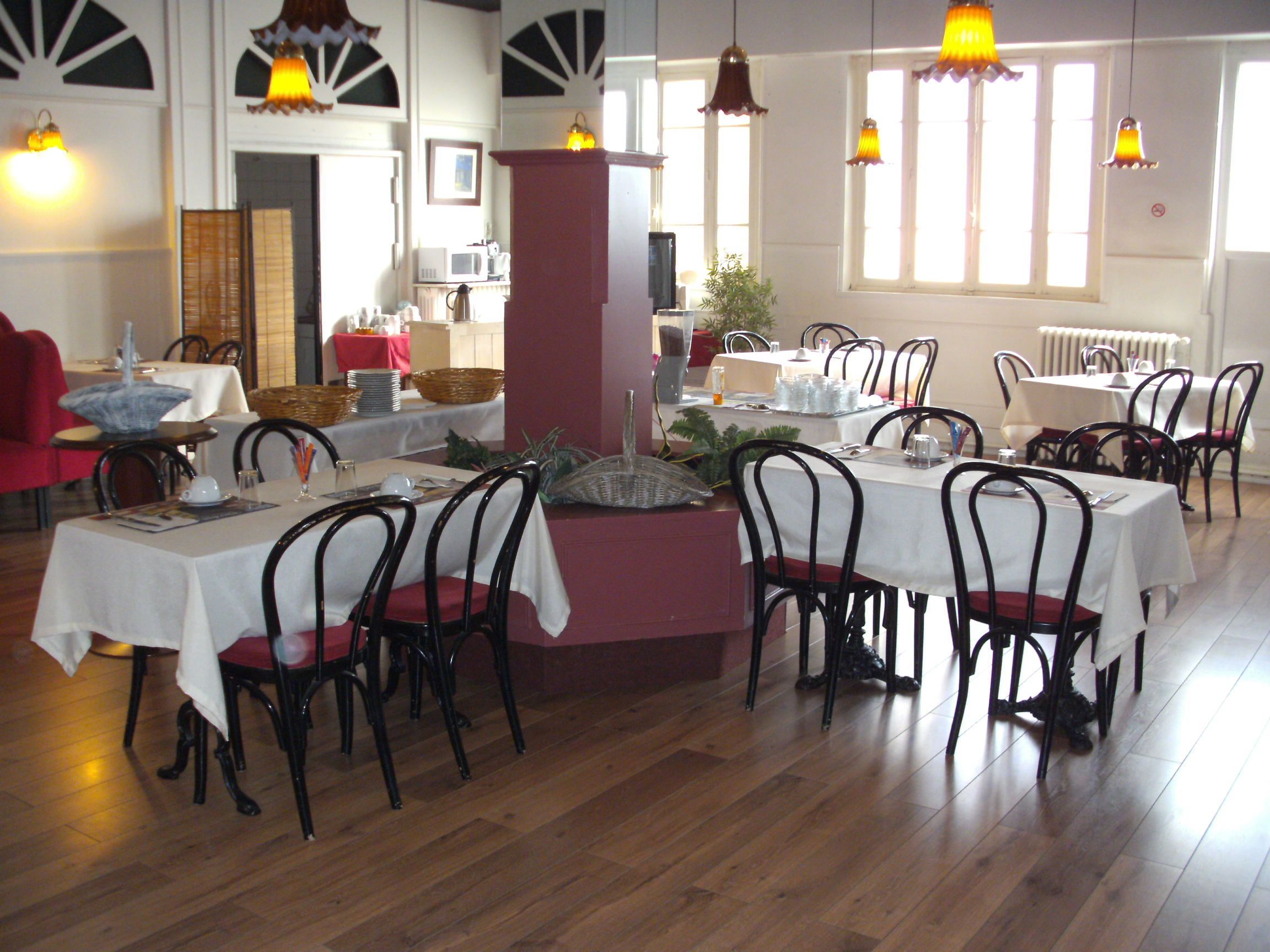 A dining area with tables set for service, chairs, and a central column.