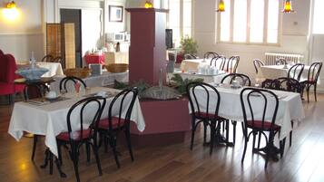 A dining area with tables set for service, chairs, and a central column.