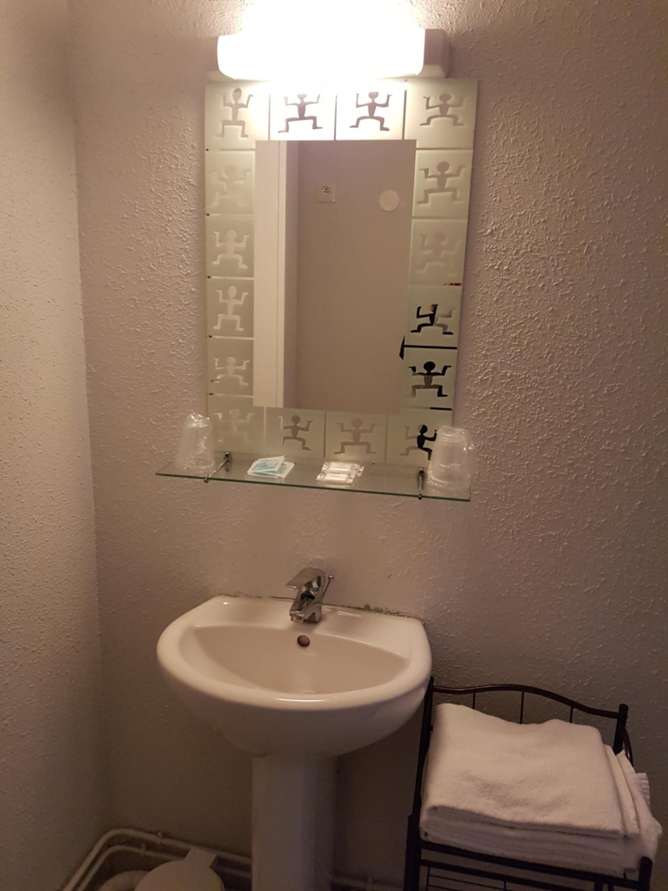 A bathroom with a white sink, a mirror with exercise figures, and a towel rack.