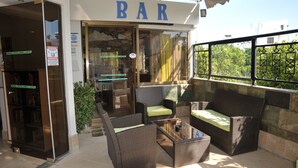 A bar area with wicker furniture and a glass table, outside a hotel with a sign reading "BAR". - Anseli Hotel (Rhodes)