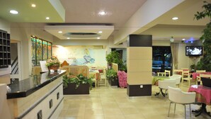 A hotel lobby with a reception desk, seating area, and a television screen. - Anseli Hotel (Rhodes)