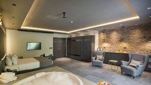 A modern hotel room with a large bathtub, a sofa, a dining area, and a TV. - Cityloft 24 (Istanbul)