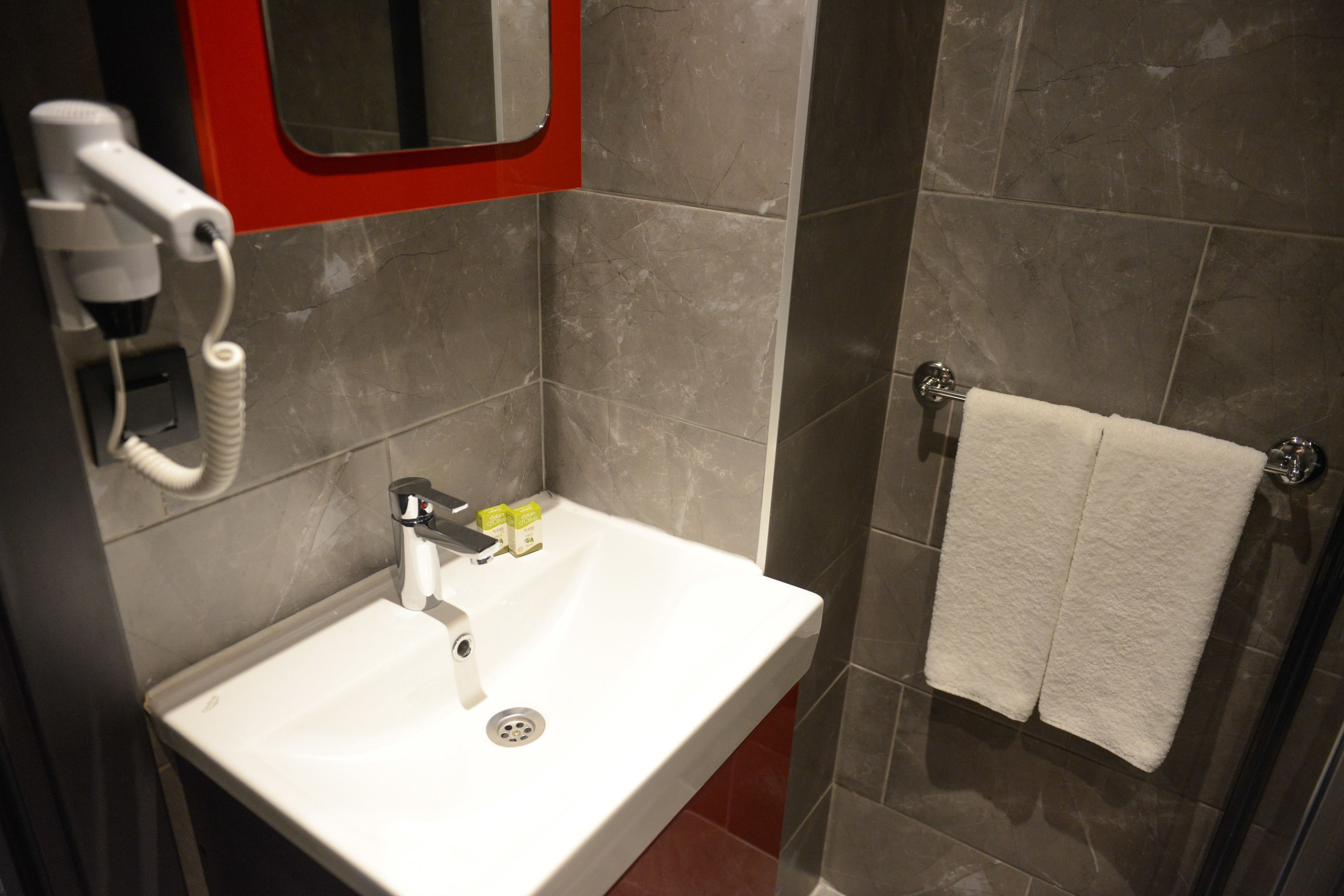 A bathroom with a white sink, a hairdryer, and a towel rack.