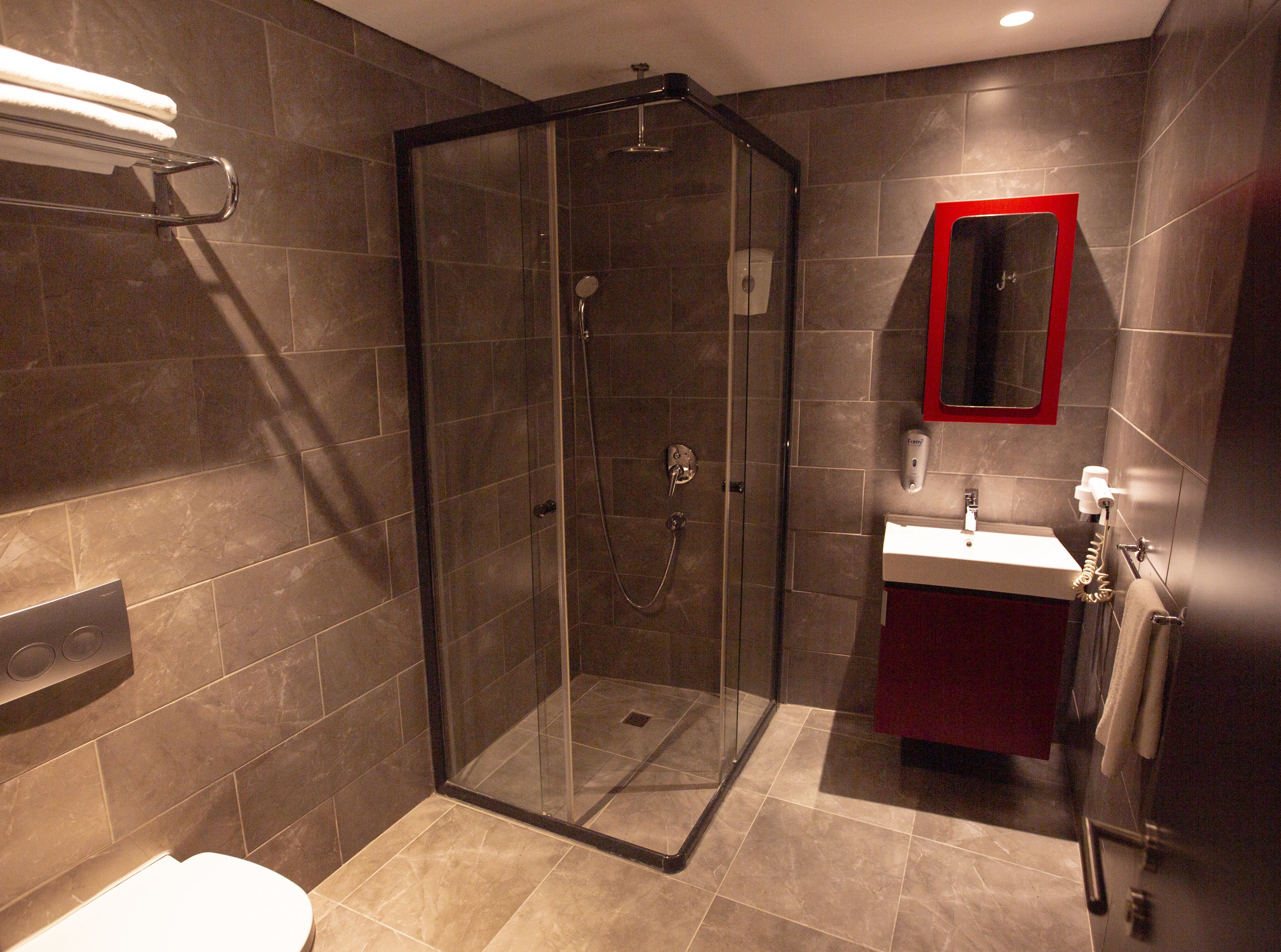 A modern bathroom with a glass-enclosed shower, a sink, and a toilet.