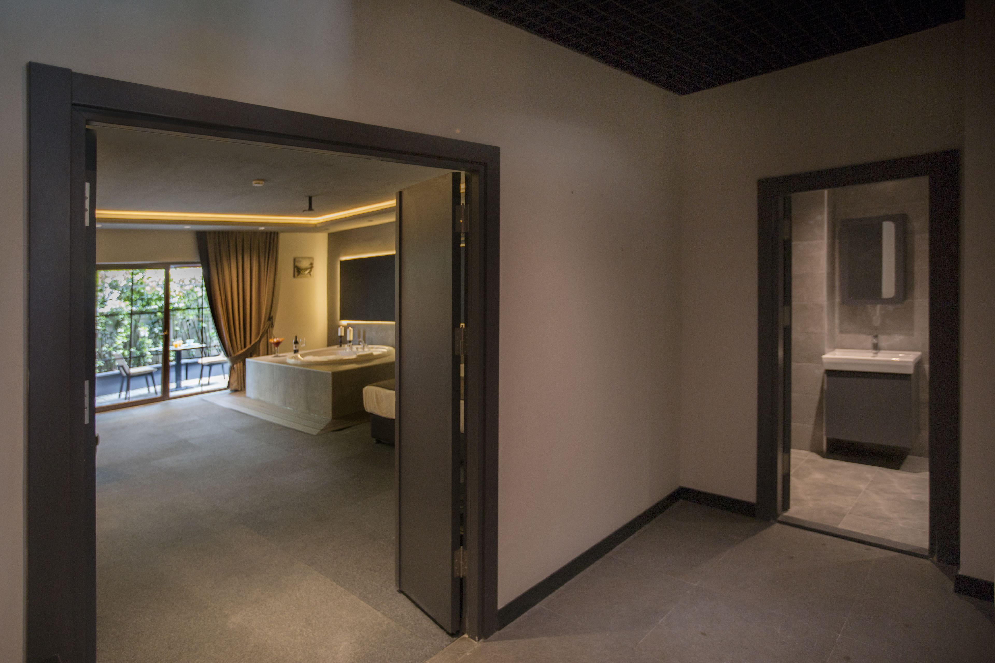Una habitación de hotel moderna con un ventanal grande, un baño con bañera y una zona de ducha independiente.