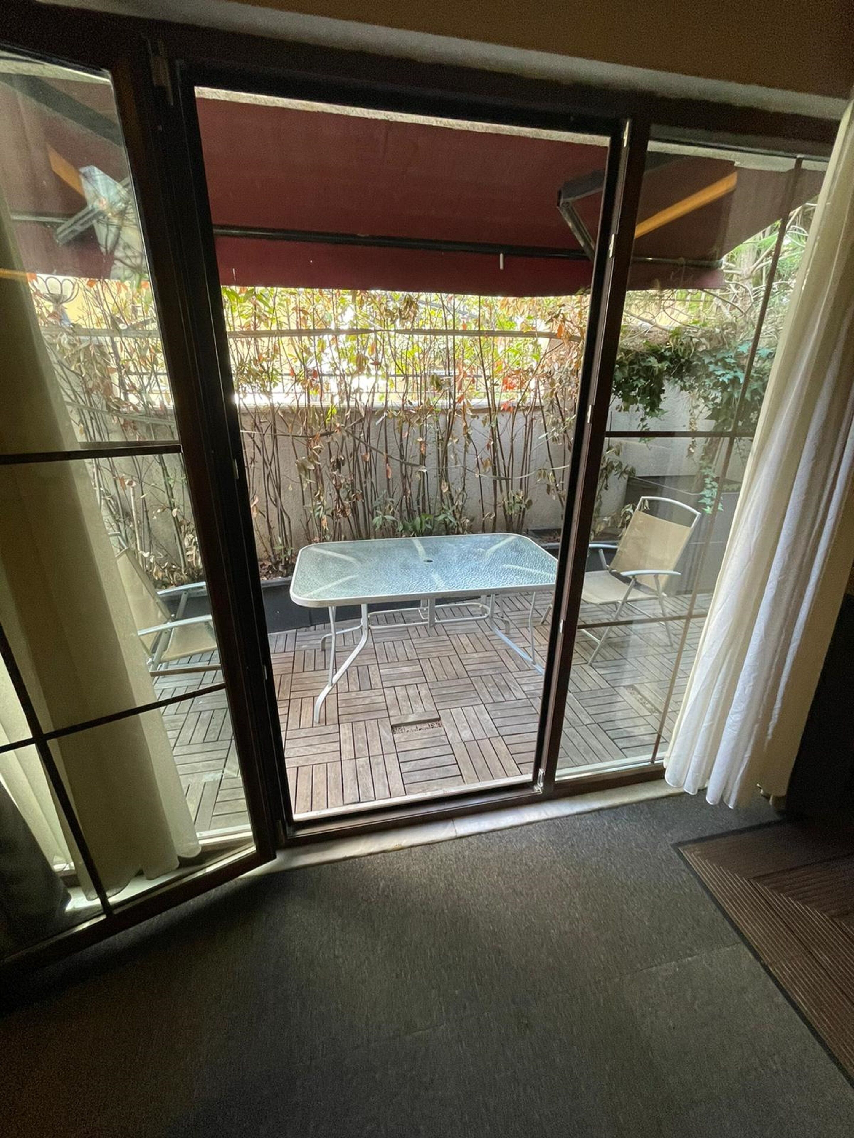 A glass door leading to an outdoor patio area with a table and chairs.