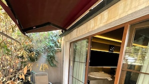 A patio with a glass table and chairs, a red awning, and a sliding glass door leading to a room. - Cityloft 24 (Istanbul)