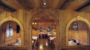 Een houten interieur met boogvormige doorgangen, tafels en stoelen klaar voor een diner.
