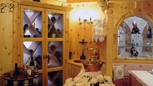 Een houten interieur met een wijnrek, een tafel met bloemen en een raam met uitzicht op een andere kamer.
