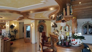 Een ruime binnenruimte met een bar, houten plafond en een open haard.