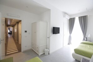 Een moderne hotelkamer met een bed, een kledingkast, een televisie en uitzicht op het omliggende landschap.