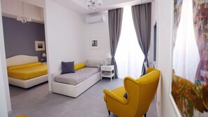 Un dormitorio moderno con una cama, un sofá, una silla y una mesita de noche.