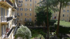 Un patio con un pequeño jardín, rodeado de edificios de varios pisos con balcones y ventanas.