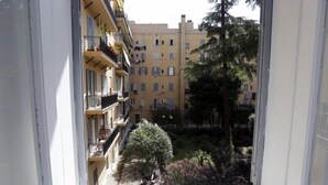 Vista de un edificio residencial de varios pisos con balcones, un patio con árboles y un cielo despejado.