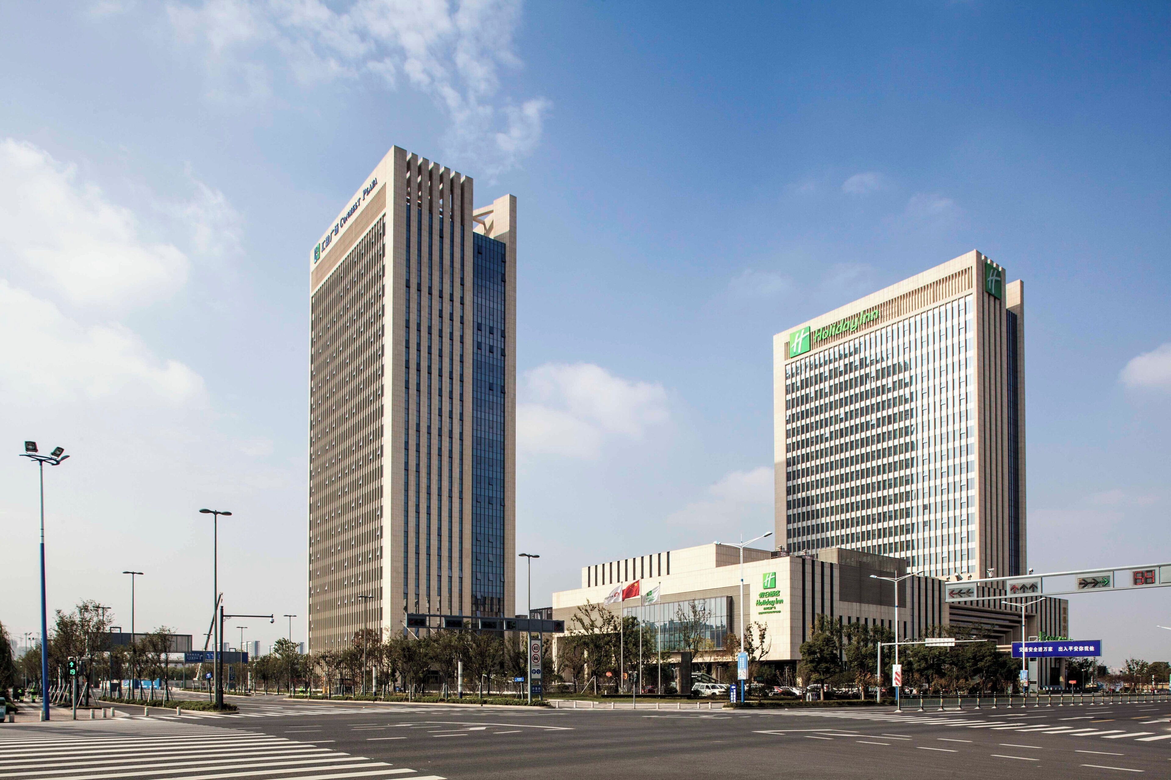 A modern hotel with a prominent vertical design, a large glass facade, and a clear sky.