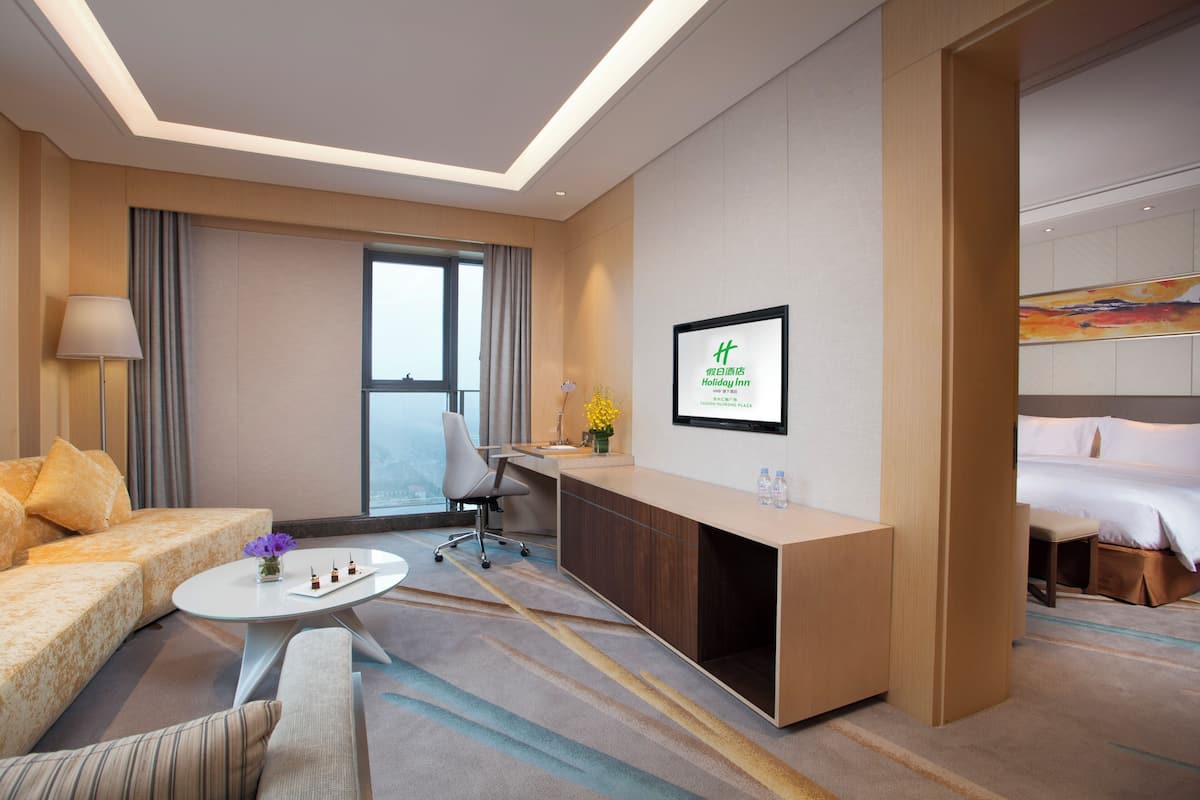A hotel room with a sofa, a desk, a chair, a coffee table, and a bed.