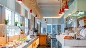 Una cocina moderna con una encimera larga, lámparas colgantes rojas y un chef trabajando.