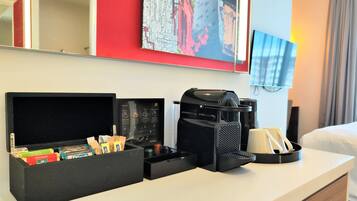 A hotel room with a minibar, a coffee maker, and a flat-screen TV.