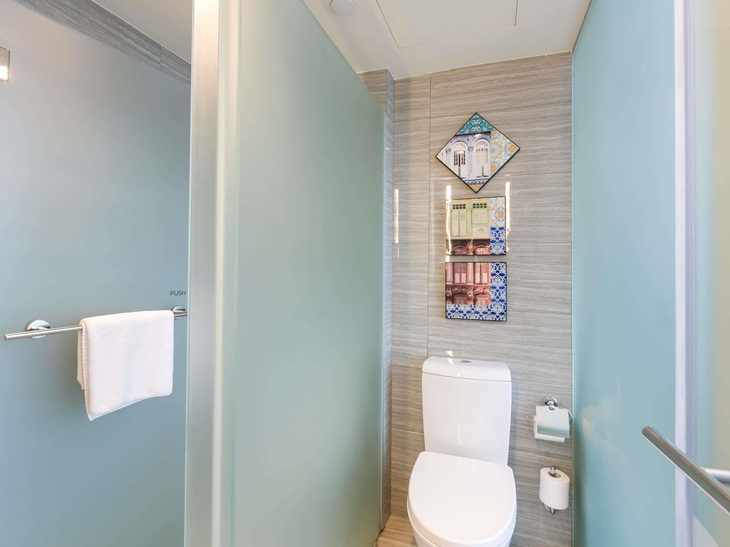 A bathroom with a toilet, a towel rack, and a decorative tile wall.