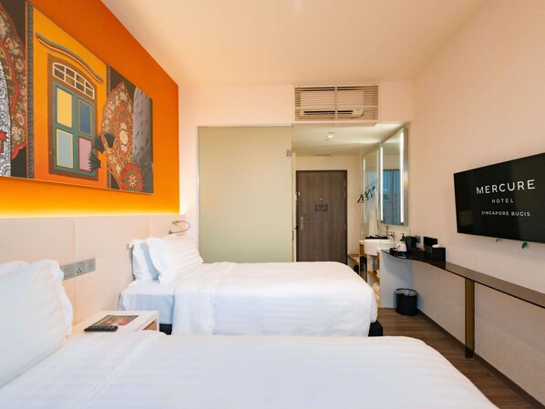 Habitación de hotel con dos camas, un espejo grande, un televisor y un cuadro en la pared.