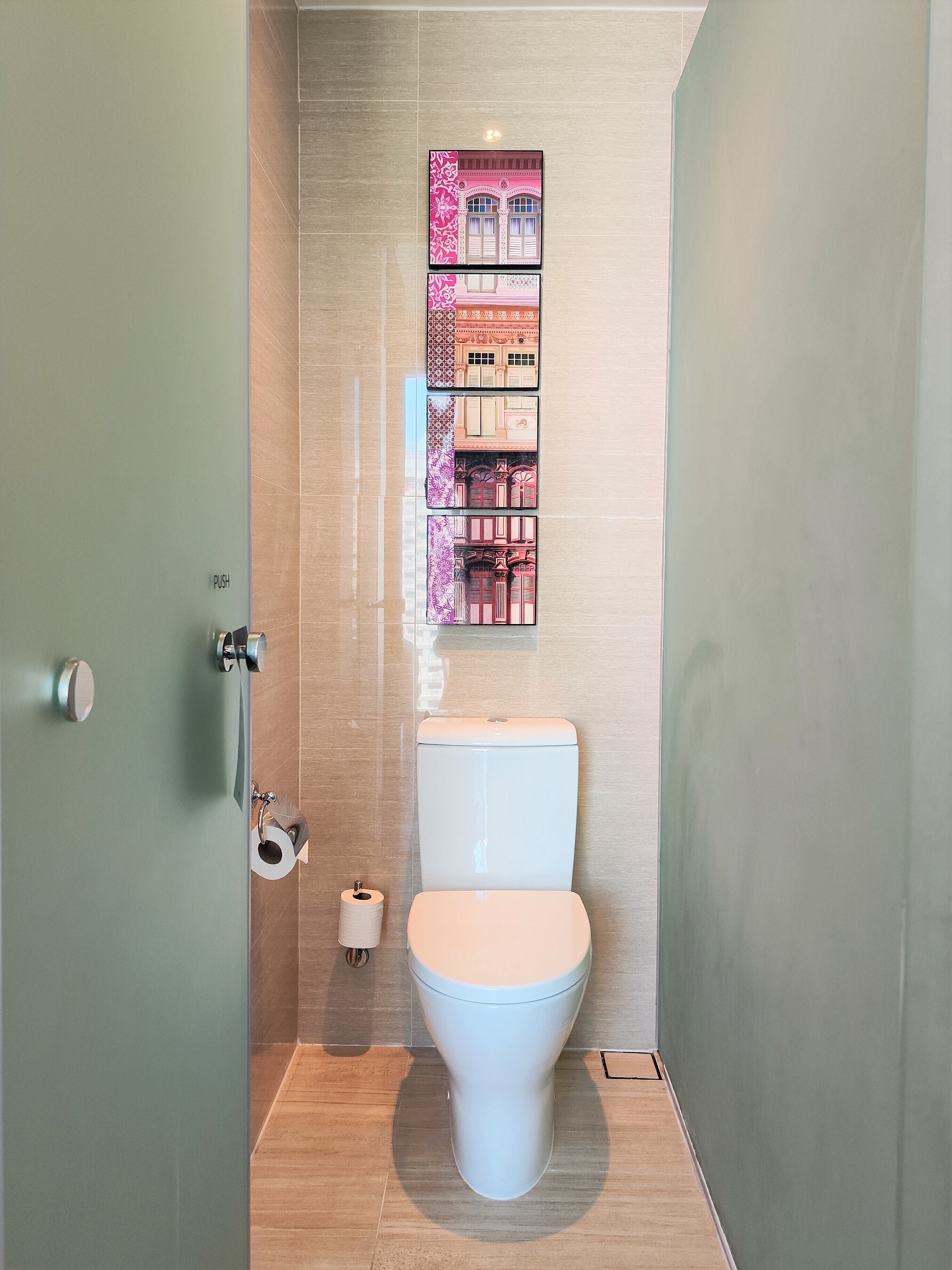 A modern bathroom with a toilet, a toilet paper holder, and a wall-mounted shelf with decorative items.