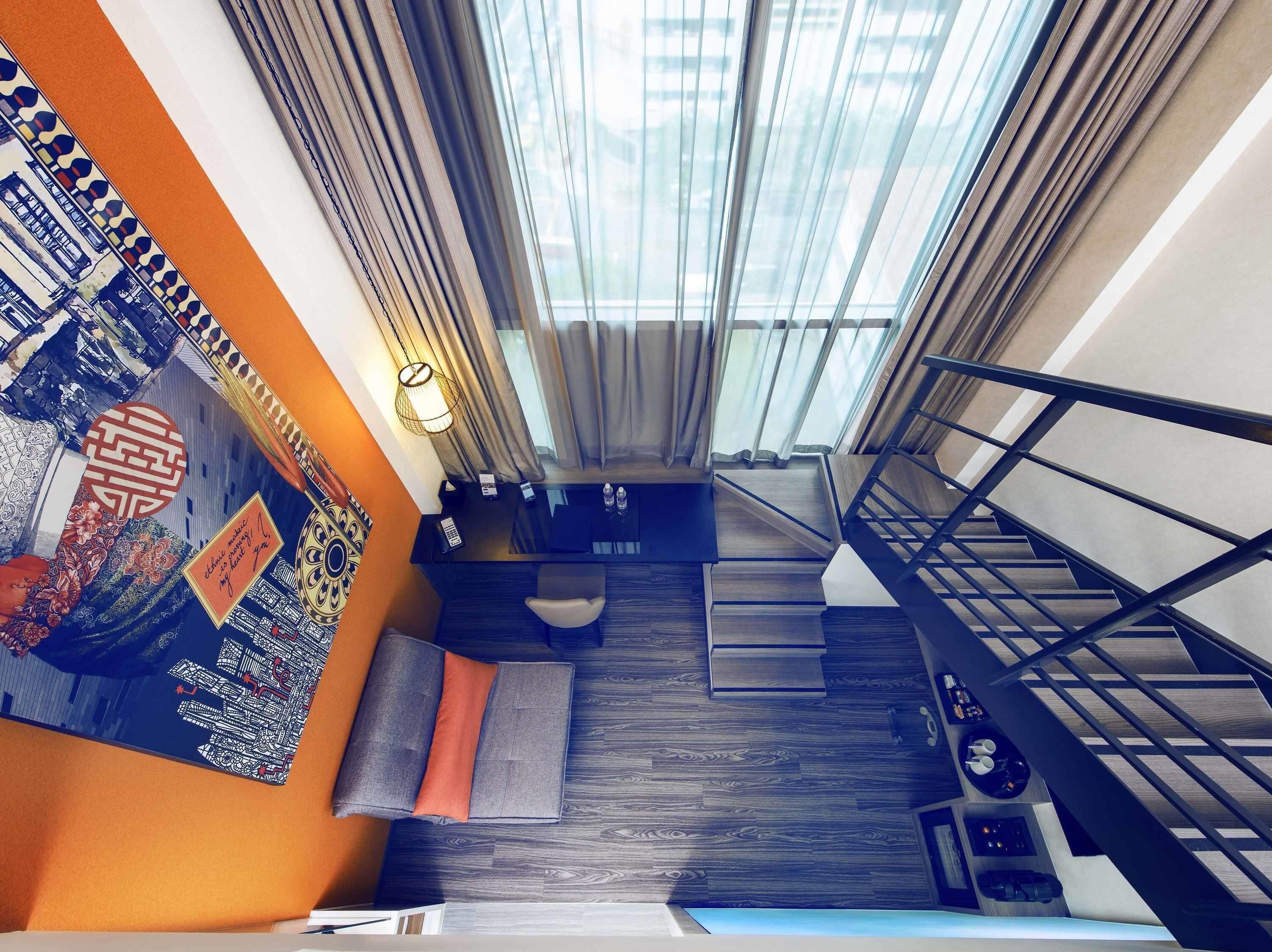 Eine moderne Treppe mit Holzvertäfelung, eine Wand mit einem Wandbild und ein Blick ins Freie durch transparente Vorhänge.