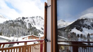 En balkon med udsigt til sneklædte bjerge og et træværksgelænder.