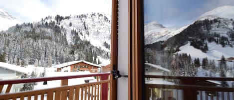Un balcón con vistas a montañas nevadas y barandilla de madera.
