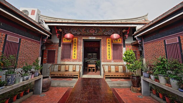 A traditional courtyard with a wooden bench, potted plants, and a tiled floor. - Tomato Red (Jinsha)