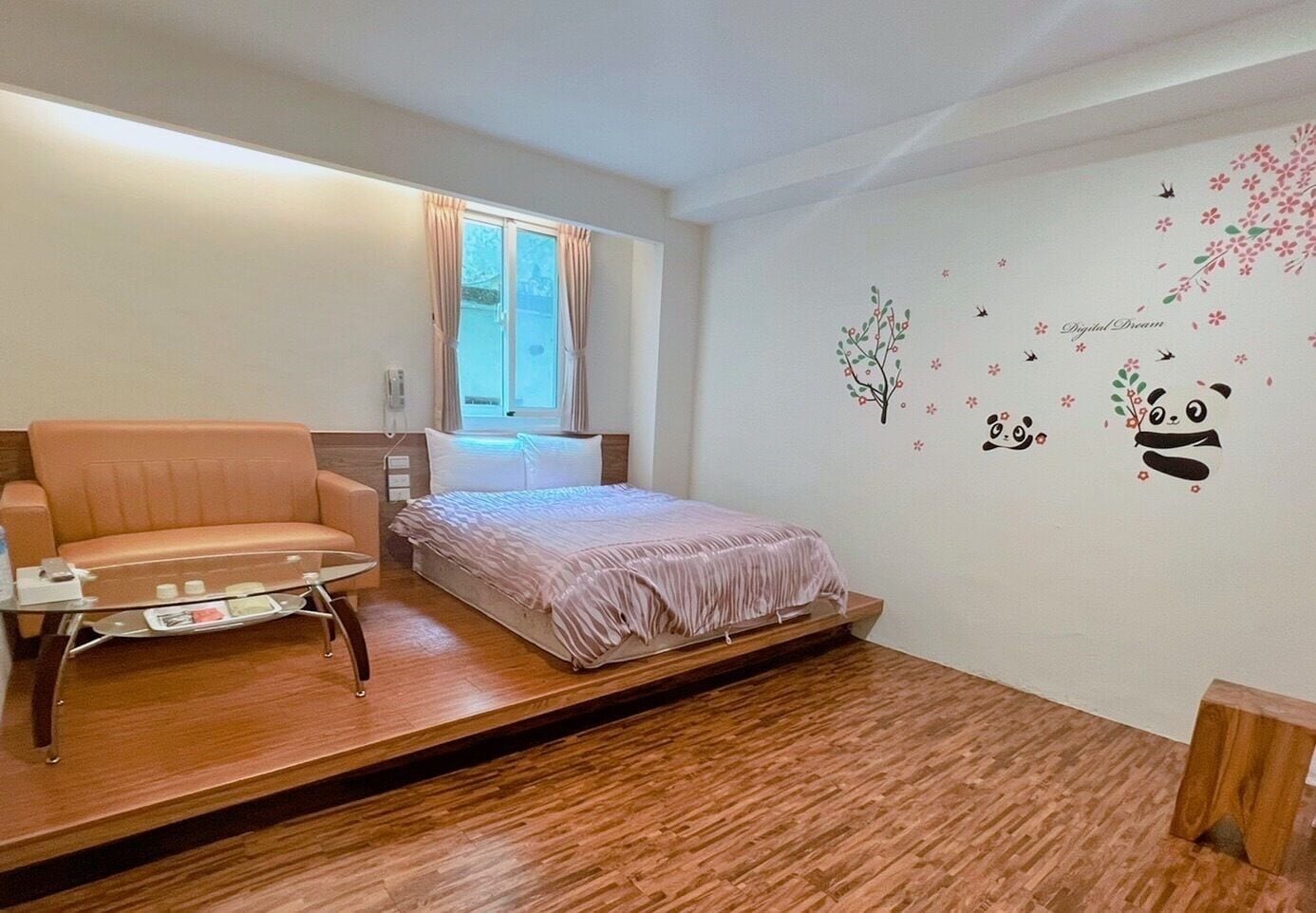 A bedroom with a bed, a sofa, a small table, and a window with curtains.