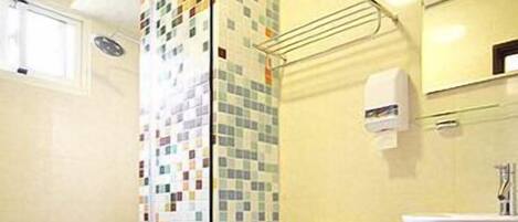 Un baño con cabina de ducha azulejada, inodoro, lavabo y espejo.