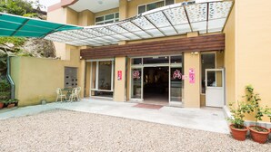 A hotel entrance with a covered patio area, a reception desk, and potted plants. - Shangti (Lugu)