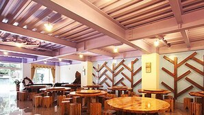 A restaurant with wooden tables and chairs, a high ceiling with exposed beams, and a chevron-patterned wall. - Shangti (Lugu)