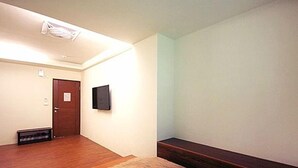 A room with a wooden floor, a door, a wall-mounted TV, and a bench. - Shangti (Lugu)