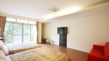 A hotel room with two beds, a TV, a red chair, and a balcony with curtains.