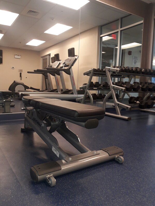 Une salle de sport équipée de tapis de course, d’haltères et de poids.