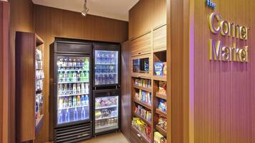 Een buurtwinkel met drankkoelingen en schappen vol snacks.